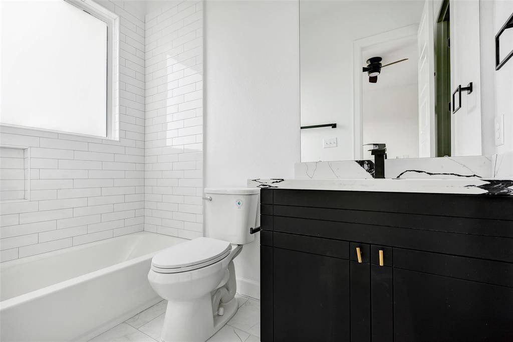 A closer look of this well-appointed bathroom, featuring a tub and shower combo, a vanity mirror, a single sink, and a convenient closet for added storage. (Model unit at 1234 E 23rd St. Design and finishes may vary)