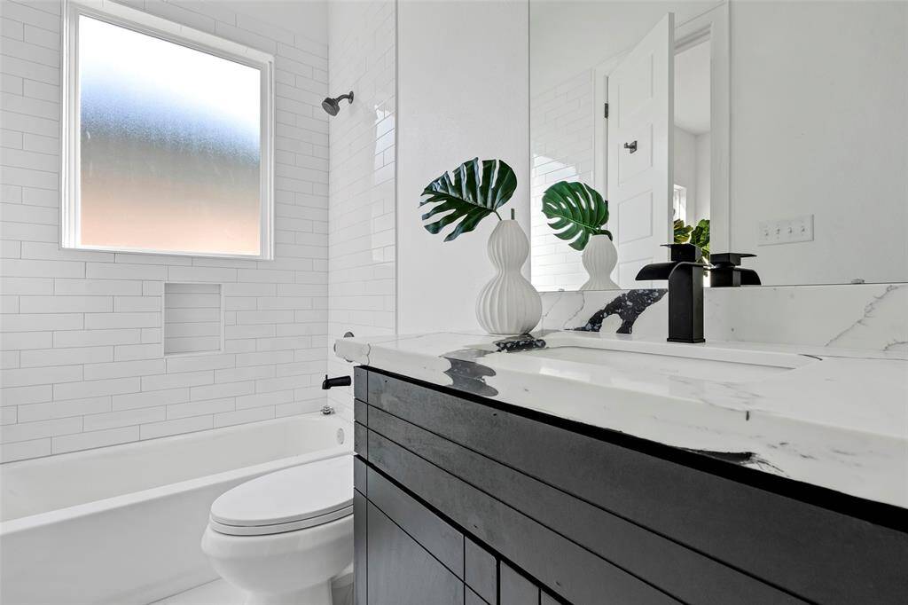 Relax and unwind in this spacious secondary bathroom, featuring a convenient tub and shower combo. (Model unit at 1234 E 23rd St. Design and finishes may vary)
