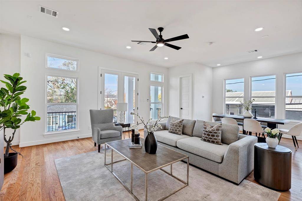 Bright and airy, this spacious living room is filled with natural light streaming through large glass windows, creating a warm and inviting atmosphere. (Model unit at 1234 E 23rd St. Design and finishes may vary)