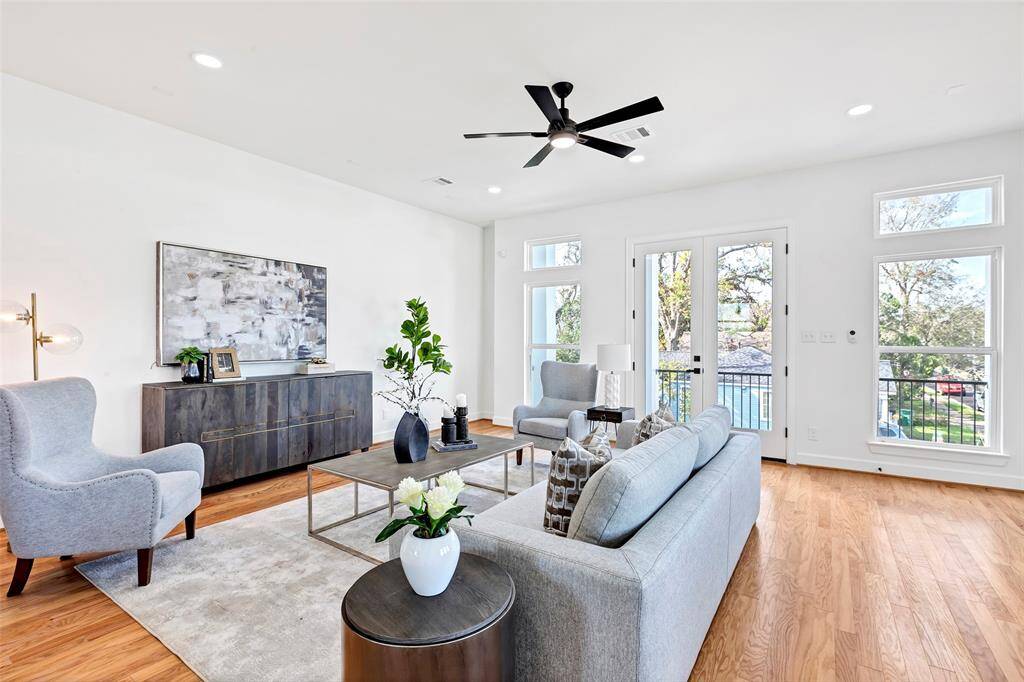Another angle of this stunning living room, featuring beautiful wooden floors and direct access to the balcony, perfect for indoor-outdoor living. (Model unit at 1234 E 23rd St. Design and finishes may vary)