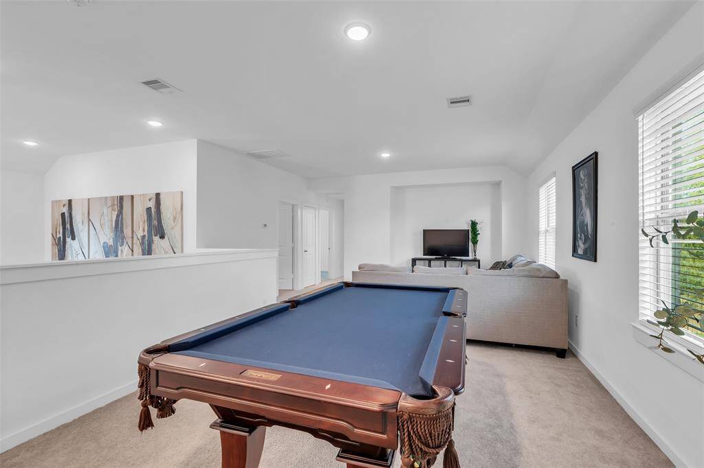 The spacious game room is located at the top of the stairs and overlooks the living area below, adding to the home's open and connected feel.