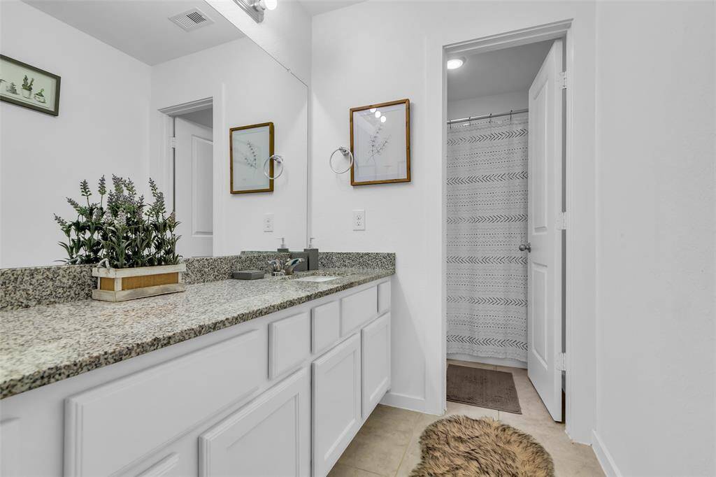 The secondary bathroom is thoughtfully designed for convenience with a separate vanity area—perfect for busy mornings. It features a granite countertop, ample built-in cabinet space, and a private shower/tub area to allow multiple people to get ready at the same time.