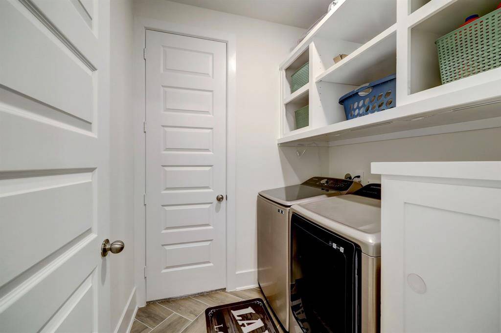 This well-organized laundry room features custom cabinetry. It has ample shelving for storage.