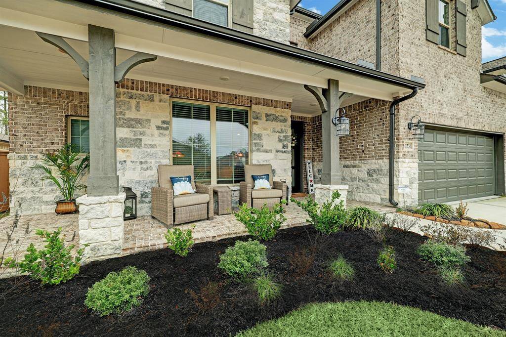 Inviting front porch with stylish brick and stone facade, complemented by pristine landscaping—ideal for relaxation and greeting guests.
