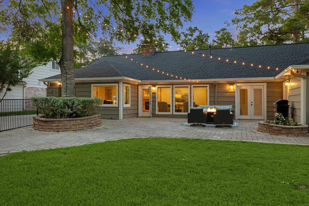 Mature trees provide shade and privacy, while string lights add warm ambiance, creating a cozy, welcoming backyard perfect for evening gatherings.