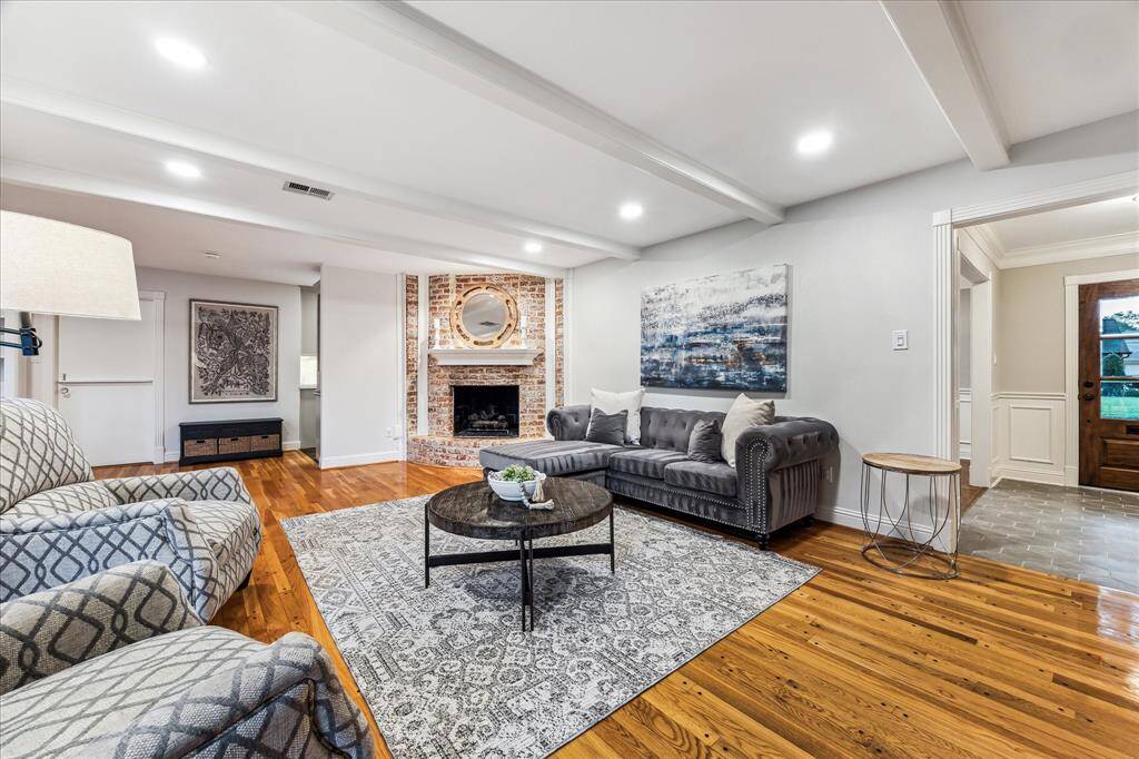 The family room features a brick-surrounded fireplace with wood beams and updated recessed lighting, creating a warm and inviting atmosphere.