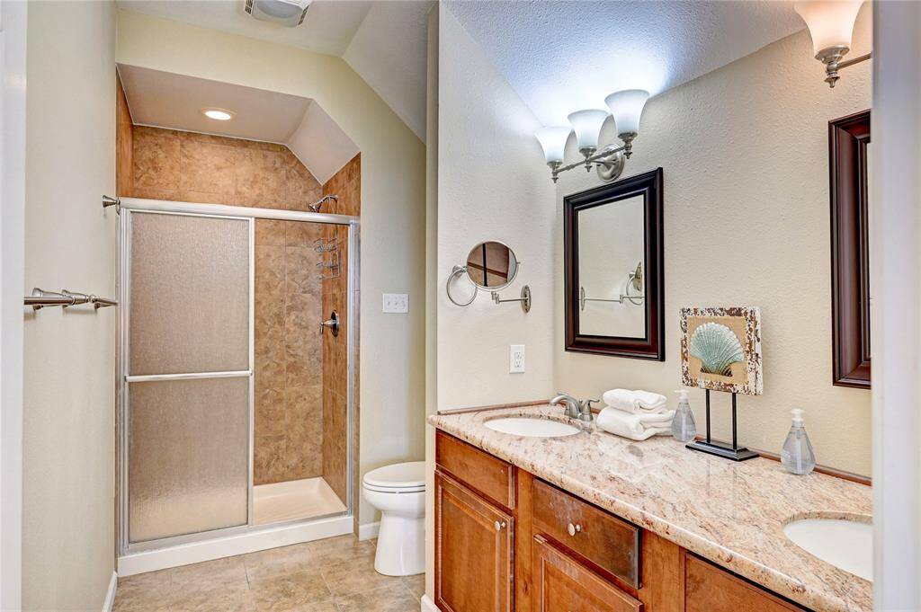 Primary suite features double vanities, a large shower stall, and a private, covered balcony.