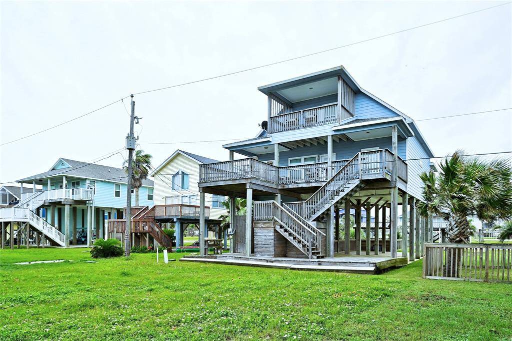 Rear elevation showing extended, covered deck on the 1st floor, the primary suite balcony, and the staircase down to the exterior entertainment space.
