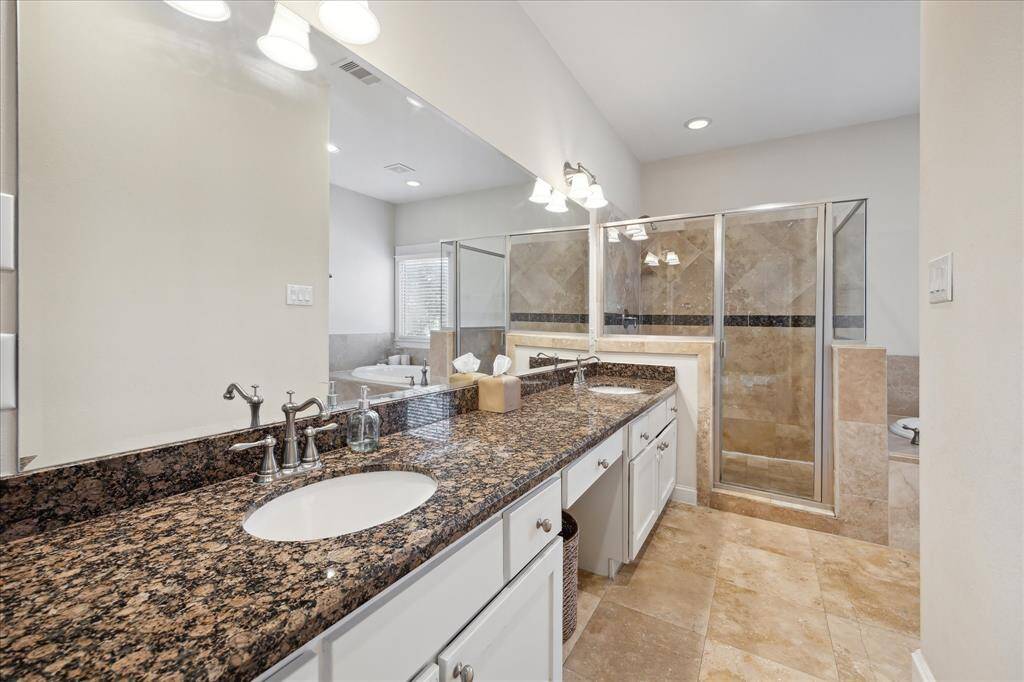 The primary bath with dual sinks, a vanity area, large walk-in shower and motion tub.