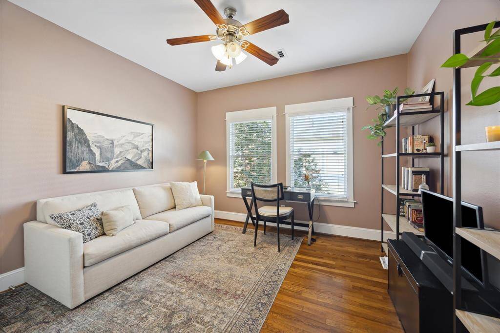 Secondary bedroom being used as a home office. Note the ceiling fan, hardwood floors and large windows.