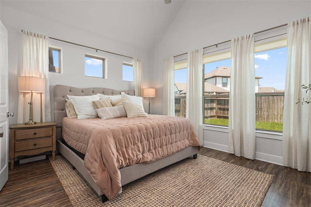 This bright bedroom features a high ceiling and large windows, offering plenty of natural light.