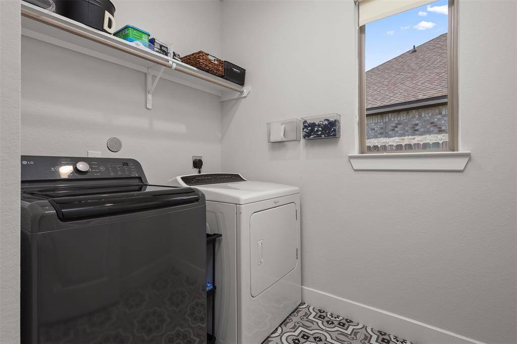 Laundry room features a window for natural light, a shelf for storage, and stylish patterned flooring.