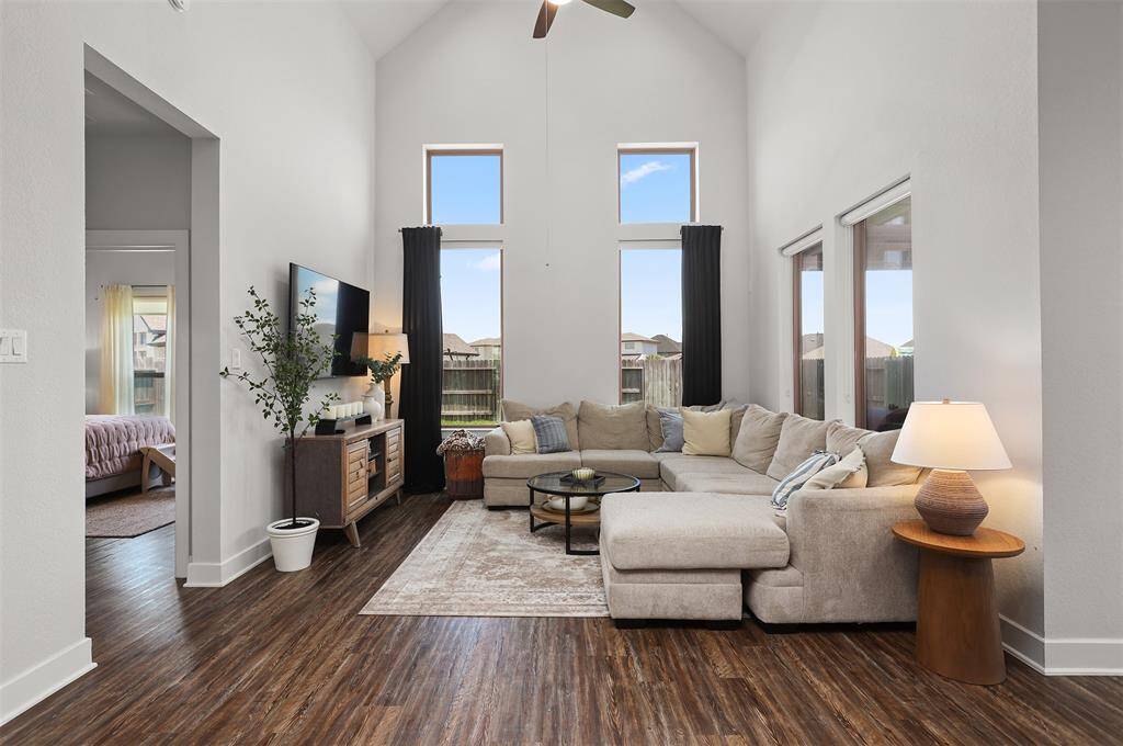 The living room features high ceilings and large windows, offering abundant natural light.
