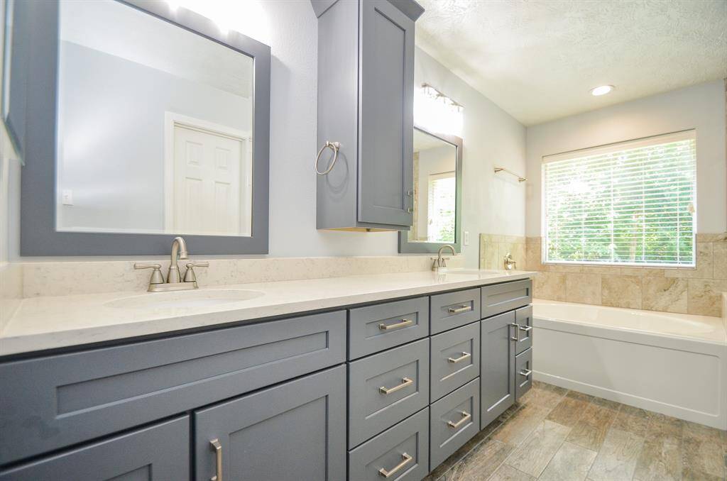 Primary bathroom with oversized vanity with double sinks, decorator mirrors and plenty of cabinets and drawers
