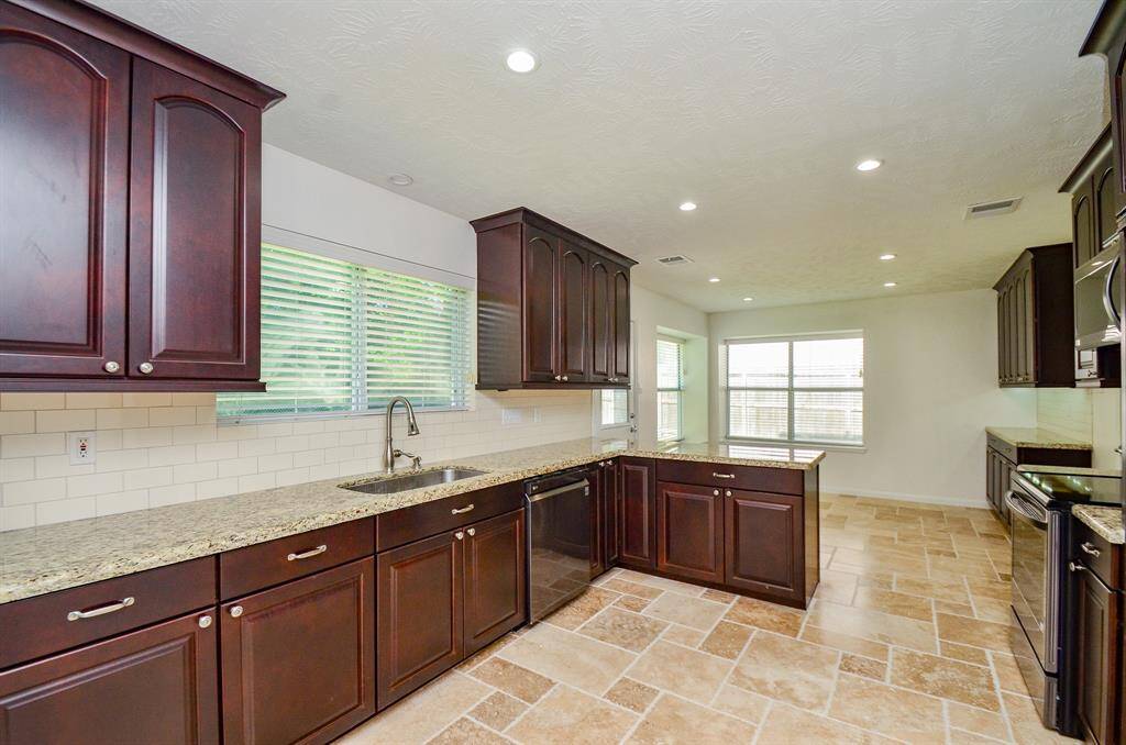 Gorgeous kitchen with granite counter tops, subway tile backsplash and an abundance of cabinets, and travertine tile floors