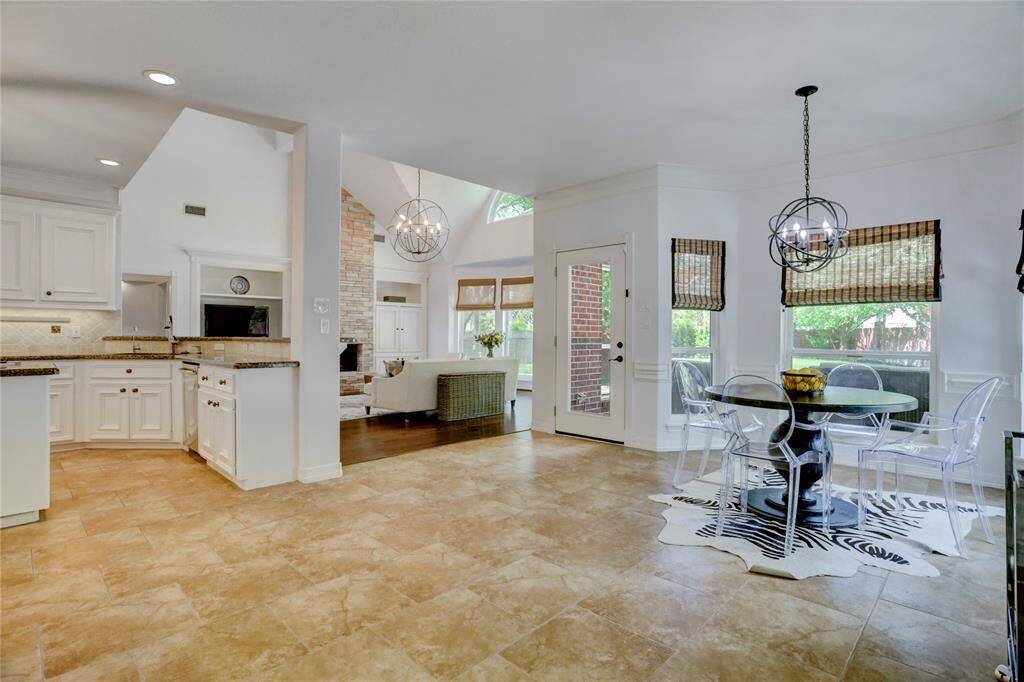 Enjoy elegance with custom shades framing large windows that overlook a vast backyard. The kitchen seamlessly connects to a bright breakfast area, featuring a modern light fixture and neutral tile flooring for a sophisticated touch.