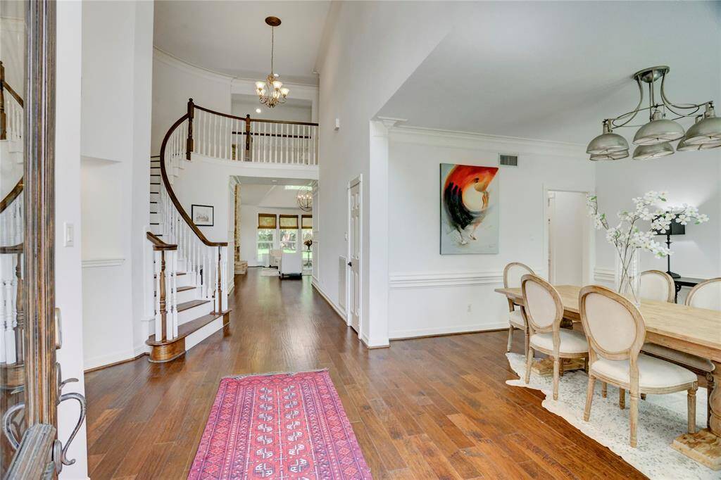 Welcome home to a stunning foyer featuring a grand curved staircase, elegant engineered hardwood floors, and soaring ceilings.