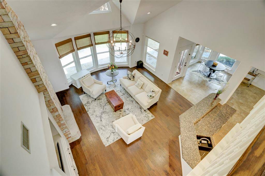 This spacious, open-concept living area features high ceilings, large windows offering plenty of natural light, and a modern design. The room includes elegant wood flooring, a cozy seating arrangement, and a view into the breakfast dining area. Perfect for entertaining and family gatherings.
