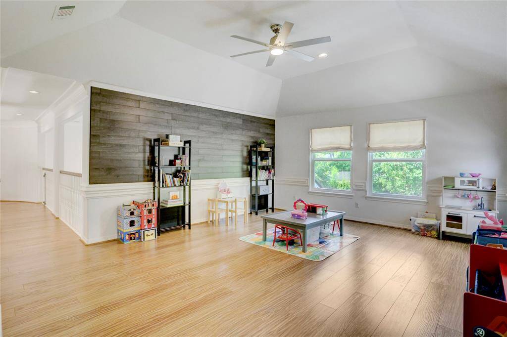 Experience the inviting gameroom with a stylish wood accent wall, elegant engineered hardwood floors, and plenty of natural light.