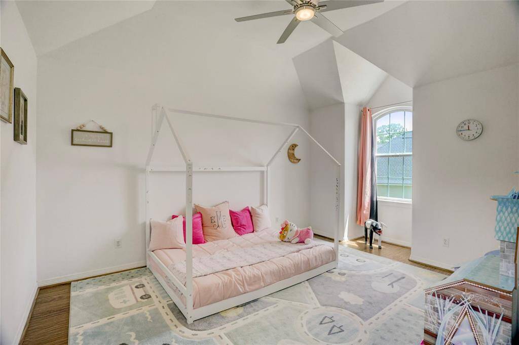 This bright and airy secondary bedroom features a vaulted ceiling and a large arched window that lets in plenty of natural light.
