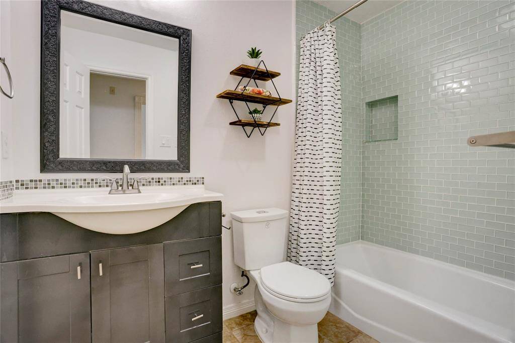 This elegant full bathroom, adjacent to the third bedroom, features a stylish glass-tiled tub and shower.