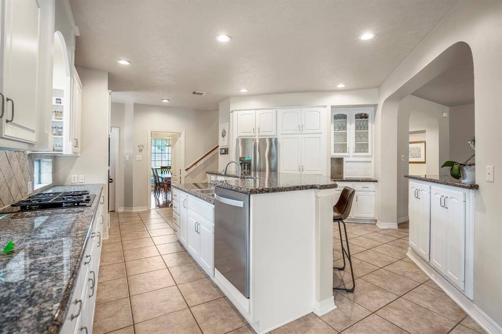 The island kitchen offers stainless steel appliances, tons of counter top place, a diagonal tiled backsplash and cabinetry which is light and bright.