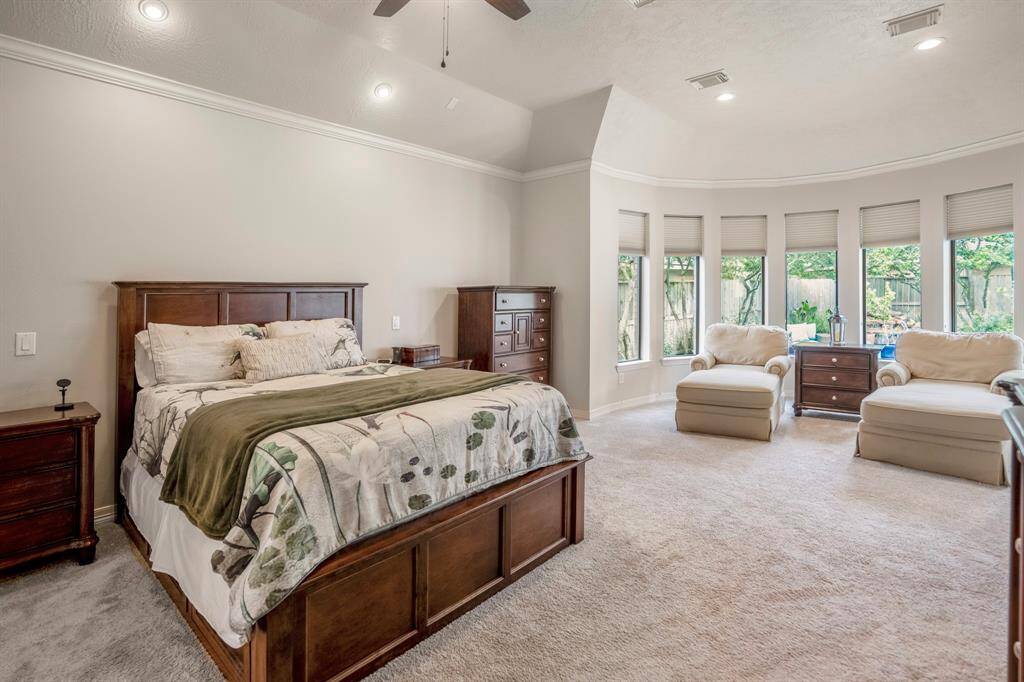 The spacious primary bedroom suite is located downstairs, featuring a large sitting area surrounded by a wall of windows offering spectacular views of the calming backyard.