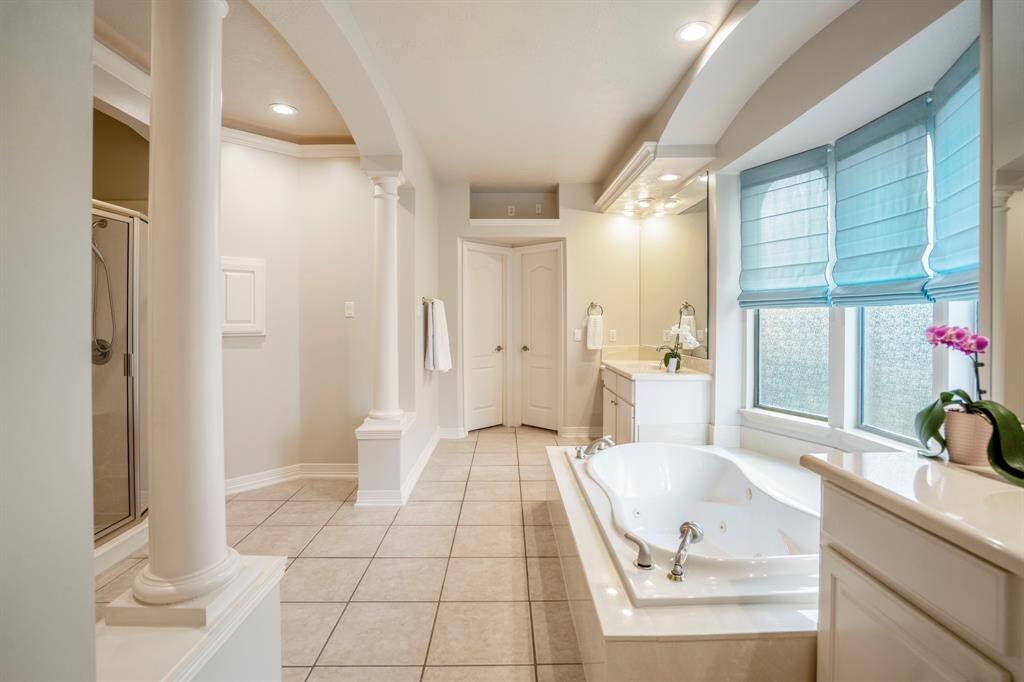 Columns elevate the primary bathroom suite to spa like status, with a large whirlpool tub nestled under three large arched defused windows.