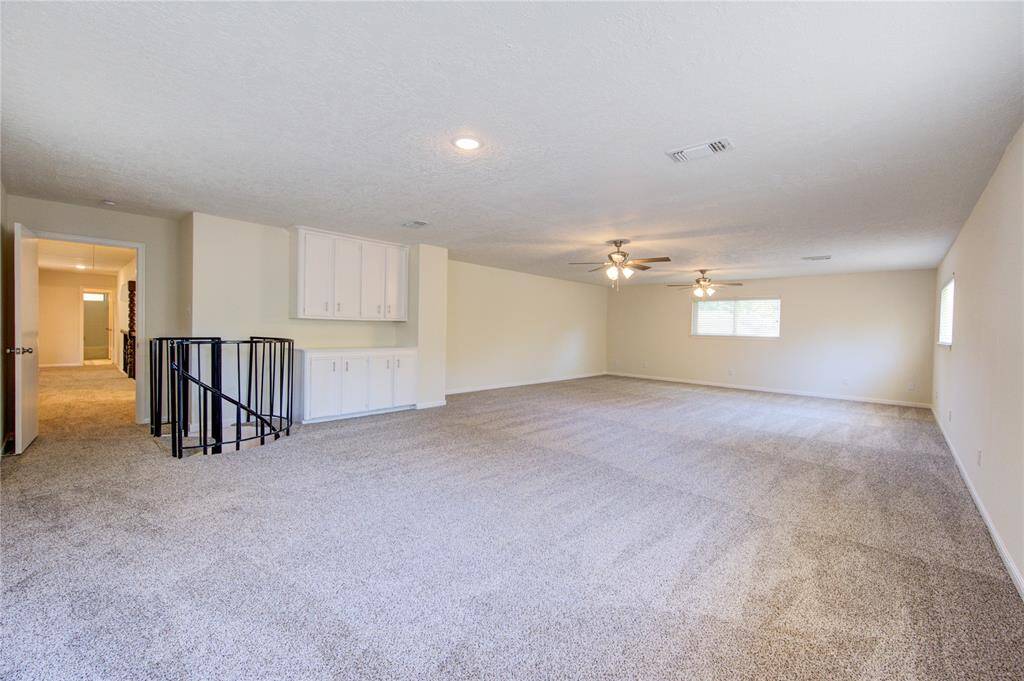 The game room spans the space over the 3-car garage and has storage cabinetry and a nifty spiral staircase leading down to the kitchen area.
