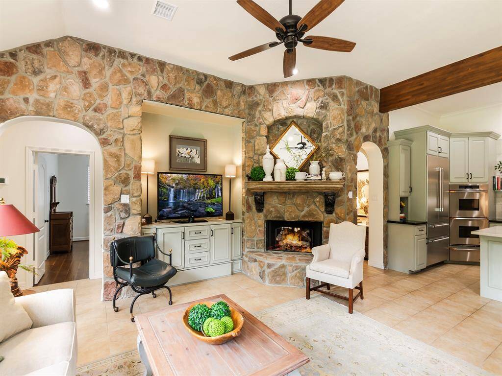 The gas log fireplace, framed by a charming stone wall with a beautiful wood mantel and stone hearth, serves as a focal point of the living room adding character and warmth to the space.