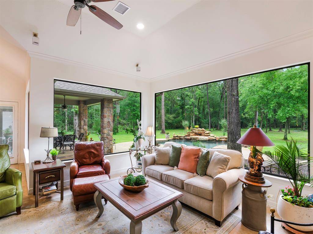 This frame of the living room showcases an L-shaped arrangement of windows, offering views of the covered patio, back-yard pool and the acreage beyond.
