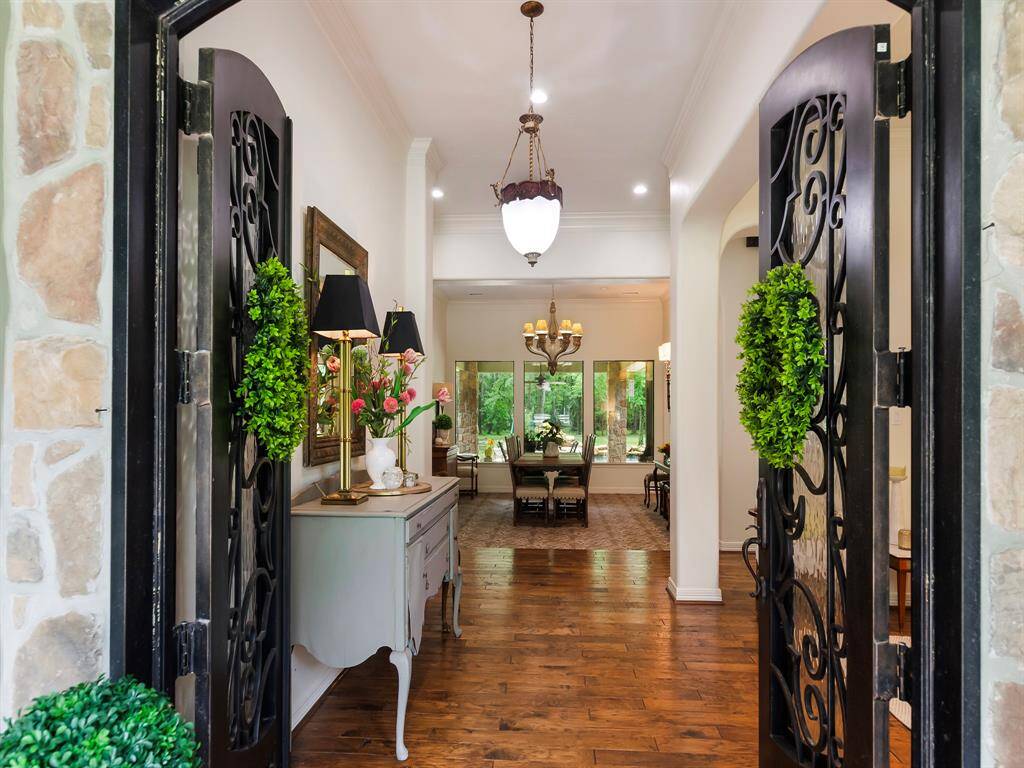 Double Cantera wrought iron and glass doors make a stunning first impression, opening to rich, hand scraped wood flooring and a welcoming foyer that flows into a beautifully styled formal dining room. Seamless, picture-perfect windows frame the captivating views of the sparkling pool and acreage beyond blending indoor elegance with outdoor serenity.