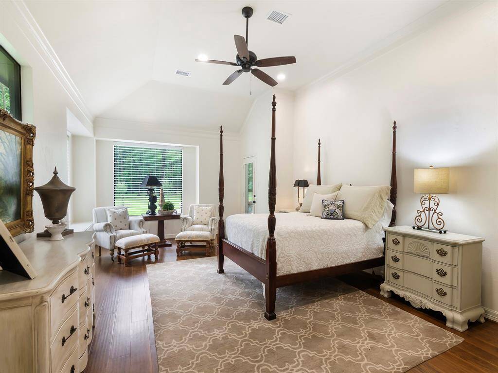This view of the owner's suite showcases a high tray ceiling, a cozy sitting area, a charming window ledge seat and two large windows allowing for the natural light. A door leads directly to the backyard offering easy access to the outdoor tranquility.