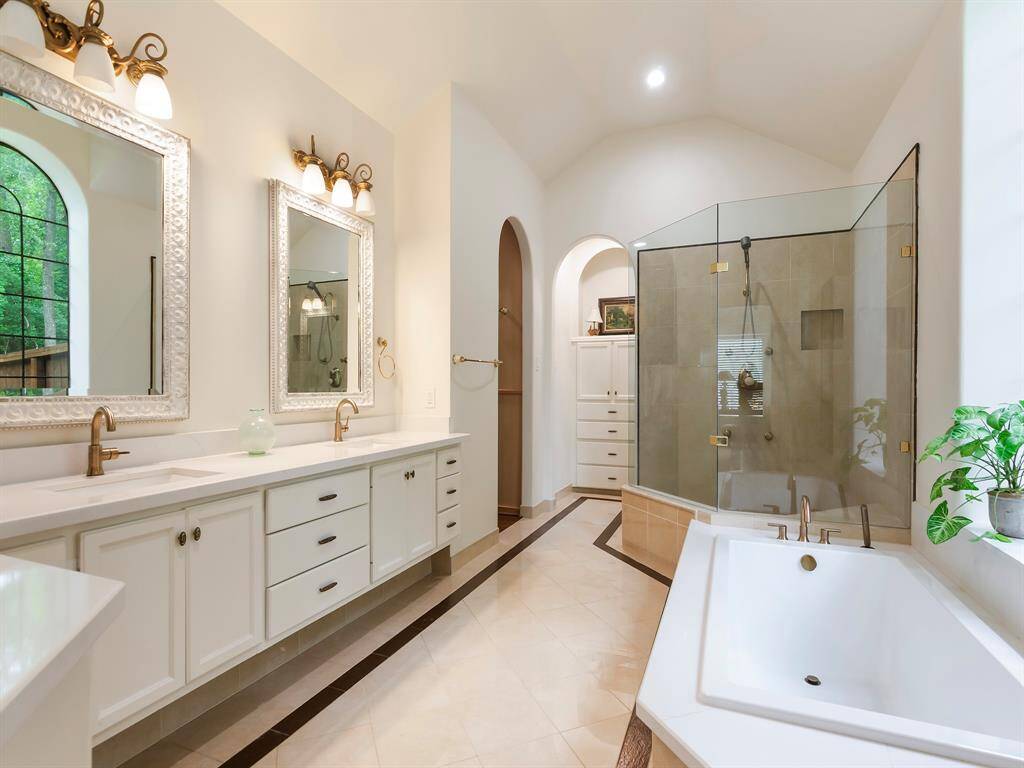 This luxurious, modernized bathroom features marble tile flooring, a big garden tub, and a glass-framed tile shower. With a built-in linen cabinet and elegant finishes throughout, it's a space you'll truly enjoy getting ready in every day.