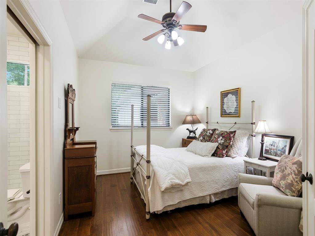 This secondary bedroom features a high ceiling, warm wood flooring, an ensuite bath and a walk-in closet.