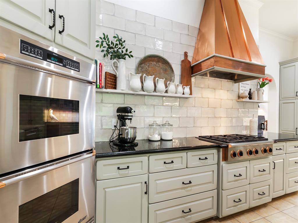 Gorgeous, sleek porcelain subway tile backsplash, lines an open wall with floating quartzite shelves above the granite countertops. Thoughtful cabinetry throughout the kitchen completes the space making it practical for storing all your kitchen items.