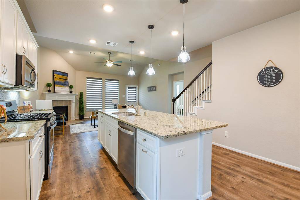 Huge picture windows bathe this spacious dining area and fantastic kitchen in pure natural light; complemented by contemporary glass pendant lighting over the center island and recessed ceiling lighting.