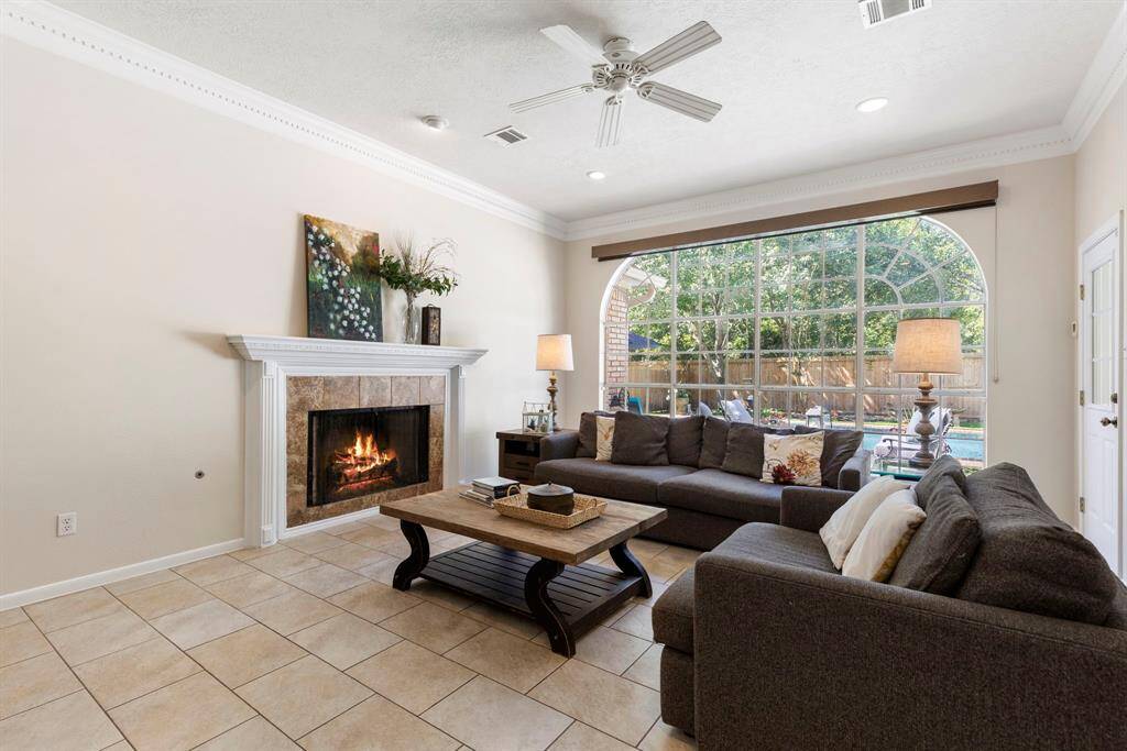 The spacious family room features a dramatic window wall with custom coverings that spans the length of the room - enjoy the amazing view of the serene pool and backyard.