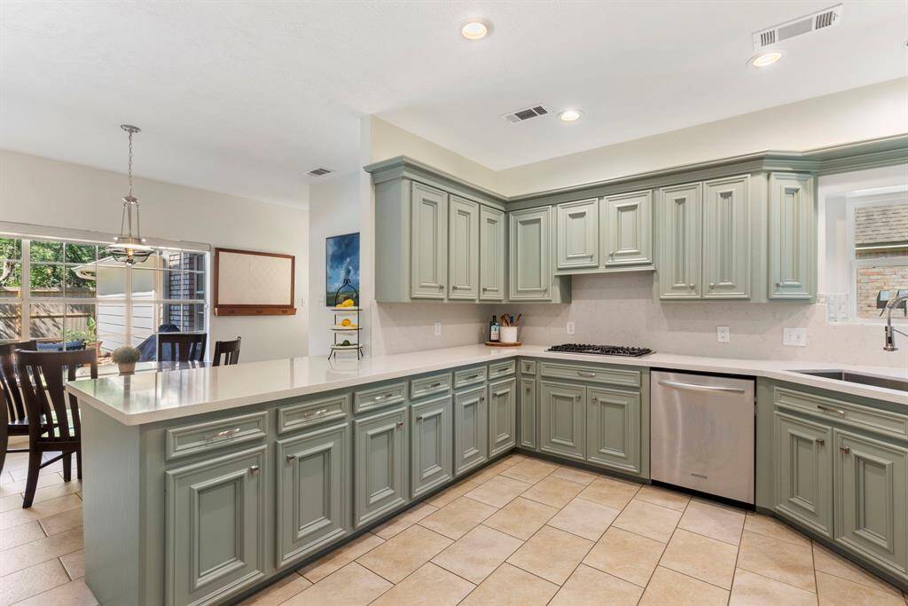 The chef’s kitchen features stunning new quartz countertops and backsplash that complement the re-finished Evergreen Fog wood cabinetry with raised panel fronts and elegant moulding.