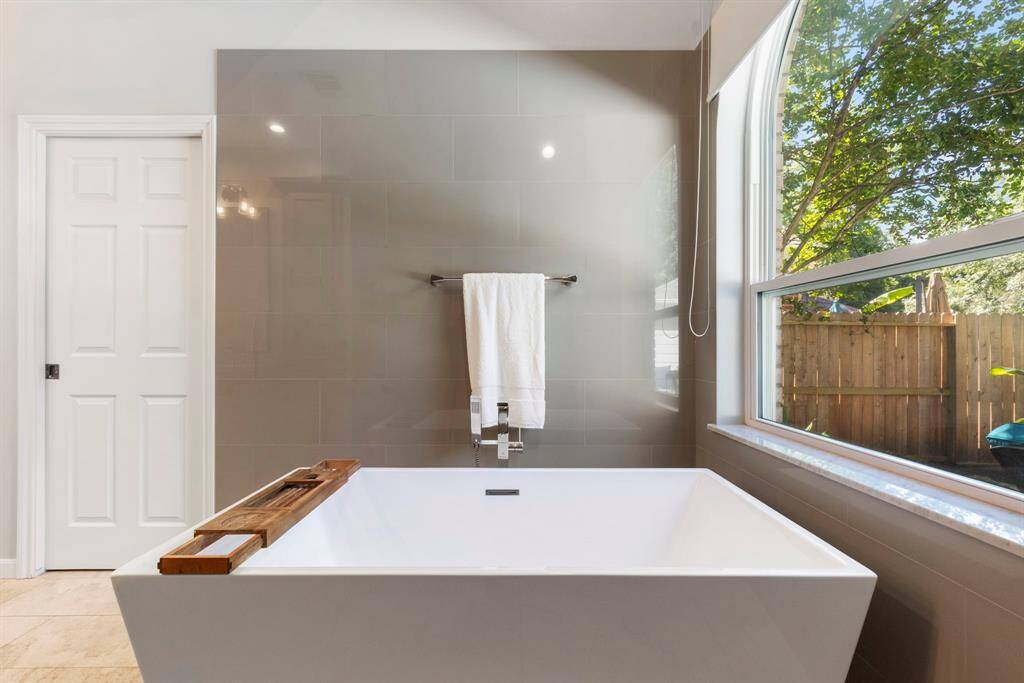 Luxurious free-standing soaker tub with tile and marble surround. The primary walk-in closet is behind the door pictured.