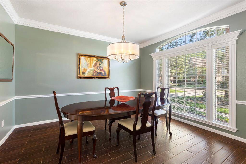 To the right of the entry, the formal dining room has wood-look tile flooring, a large cased window with front yard views, and an updated light fixture - ideal for hosting friends and family gatherings.