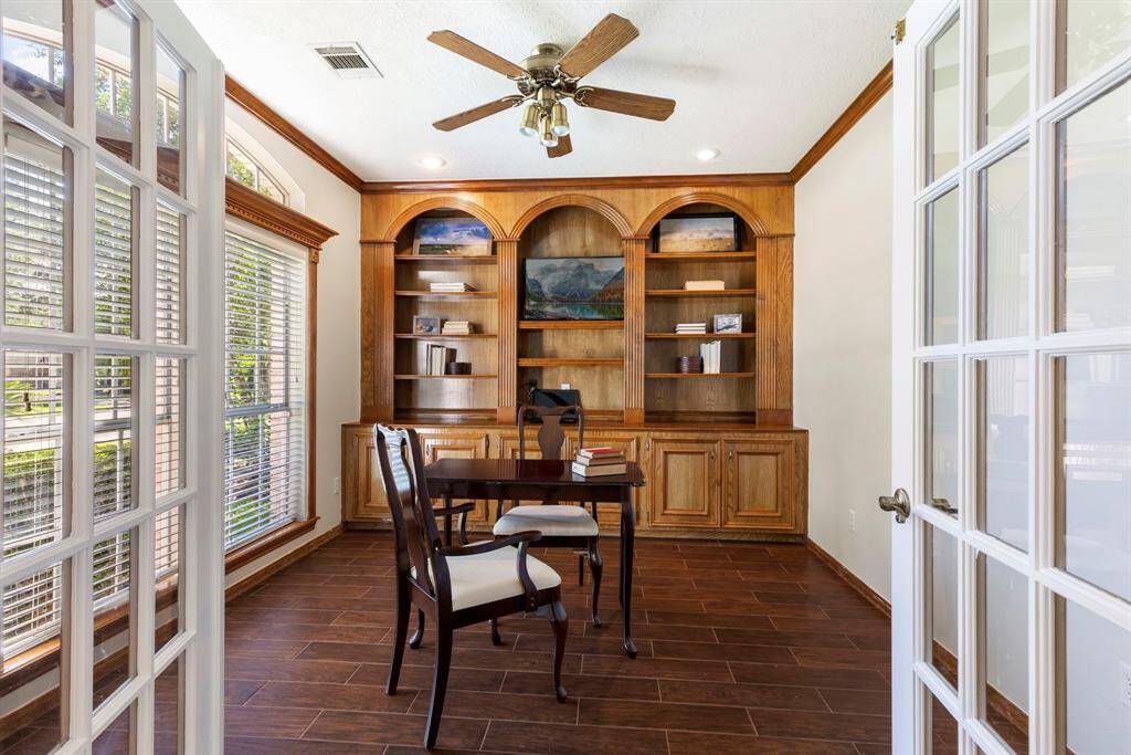 On the left of the foyer, a private study is tucked behind glass-paned French doors, highlighted by stained crown molding, window casing and a wall of custom wood stained built-ins—perfect for a private home office or library.