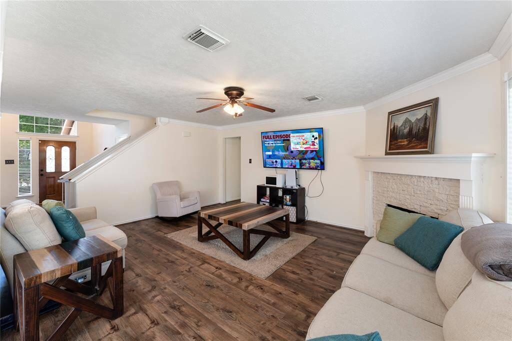 This photo showcases a modern kitchen with sleek black granite countertops, white cabinetry, and stainless steel appliances. It features an inviting breakfast bar for seating and ample natural light. The open layout connects to a cozy living area, providing a spacious and functional setting.