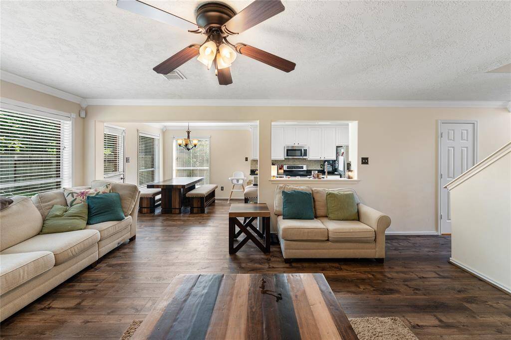 This inviting living room features a cozy fireplace, and a stylish ceiling fan. It has ample natural light, space for comfortable seating, and a mount for TV for entertainment. The space is enhanced by tasteful decor and a modern coffee table, creating a warm and welcoming atmosphere. (not included)