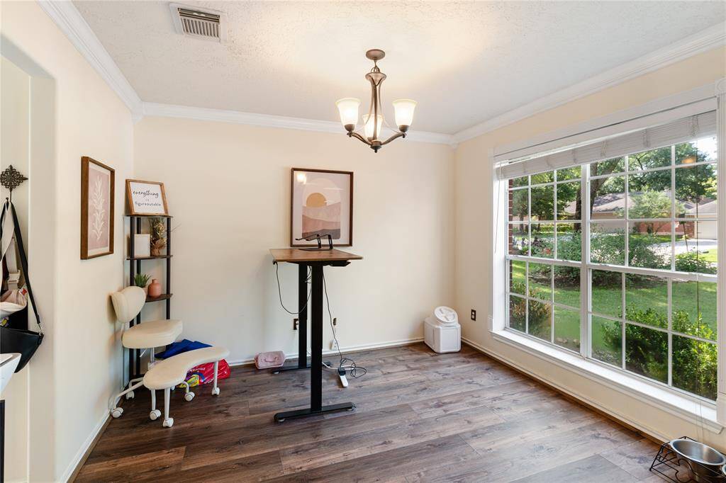 This is a charming two-story brick home with a spacious driveway leading to a two-car garage. It's surrounded by a well-maintained lawn and mature trees, offering a serene and private setting. The house features a classic architectural style with a welcoming entrance.