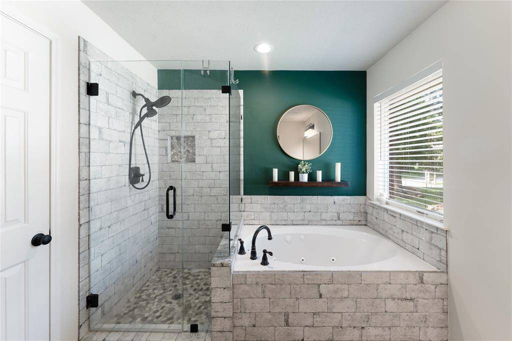 Spacious bedroom featuring a vaulted ceiling, green accent wall, and large window for natural light. Includes a ceiling fan, a place for a mounted TV, capable of holding large furniture. Cozy and inviting atmosphere.
