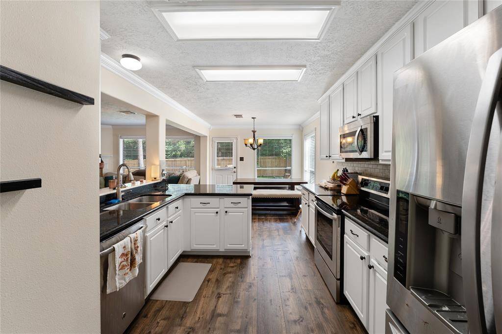 This bathroom features a modern design with a spacious layout. It includes a large walk-in shower with glass doors, a luxurious soaking tub, and a double vanity with granite countertops. The room is accented with a teal wall and wood-look flooring, offering a stylish and inviting atmosphere.