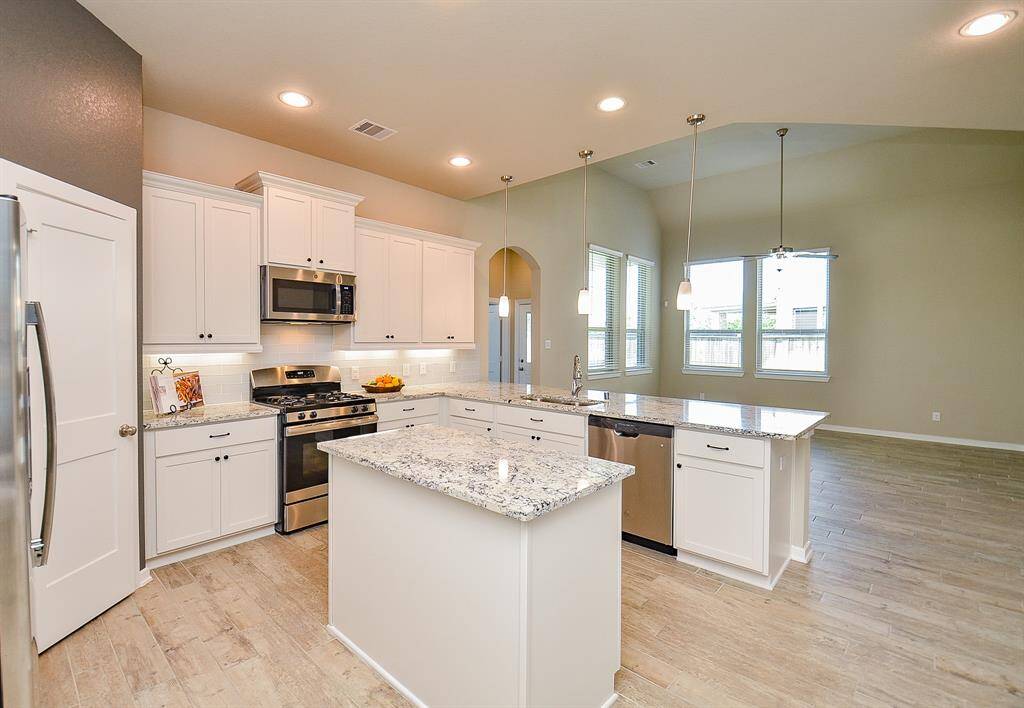 Under-cabinet lighting adds a warm glow, while a large walk-in pantry keeps everything organized and tucked away.