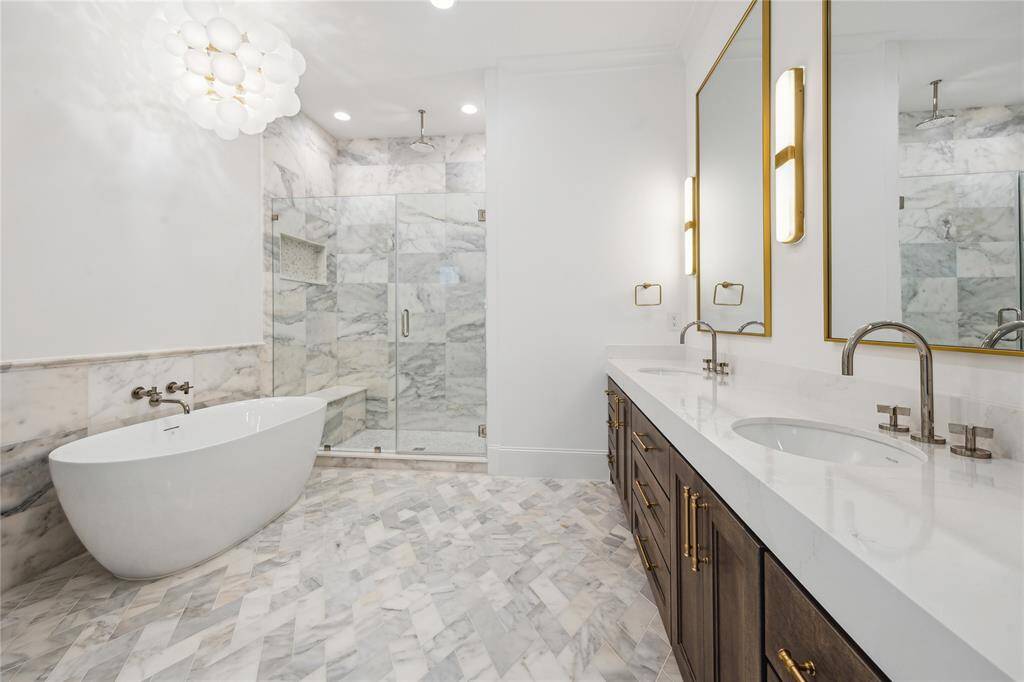 Primary bathroom features a Sterling Unwind freestanding oval soaking tub with Kallista One wall-mounted faucet, framed glass shower with Laticrete shower system, and tastefully crafted English-inspired stacked crown moldings.