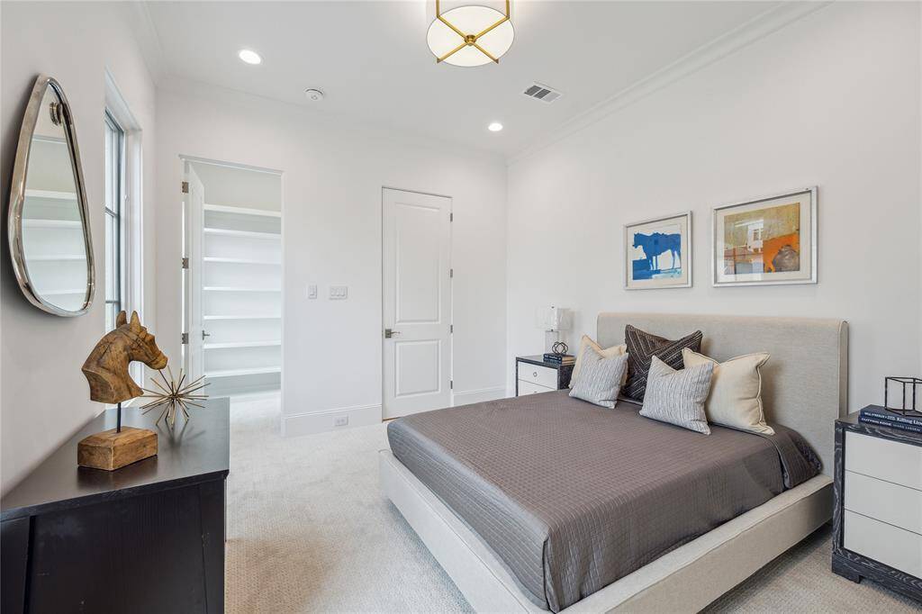 Second-floor bedroom receives ample natural light and features a spacious walk-in closet, along with Dreamweaver Pinpoint high-performance carpet and Luce aged-brass light fixture with linen shade.